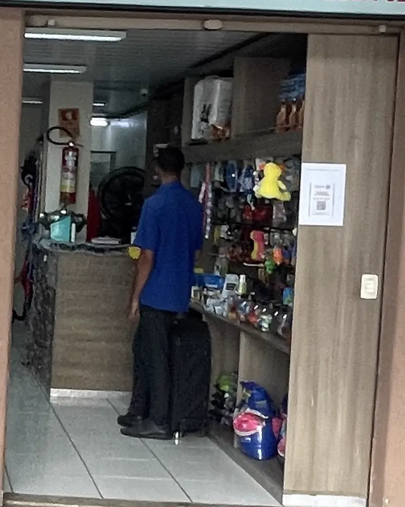 Interior do pet shop com prateleiras de rações, acessórios e brinquedos e o balcão de atendimento